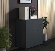 Moderne dunkelgraue Kommode mit Schubladen, dekoriert mit Büchern und Blumenvase, in Wohnraum-Setting; Perspektive: frontale Ansicht leicht von links.