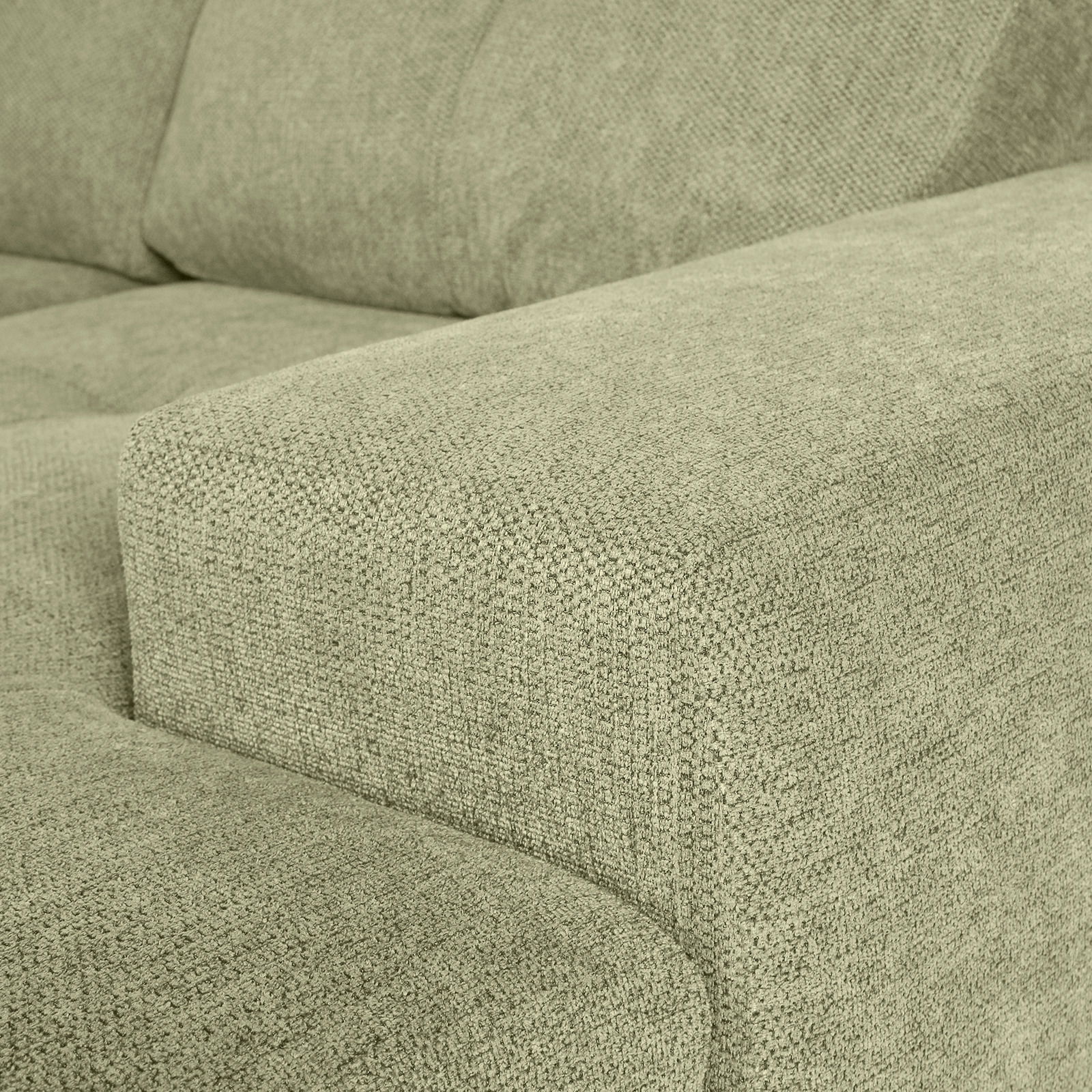 Nahaufnahme einer grünen Sofaecke mit texturierter Stoffoberfläche, Perspektive von der Seite.