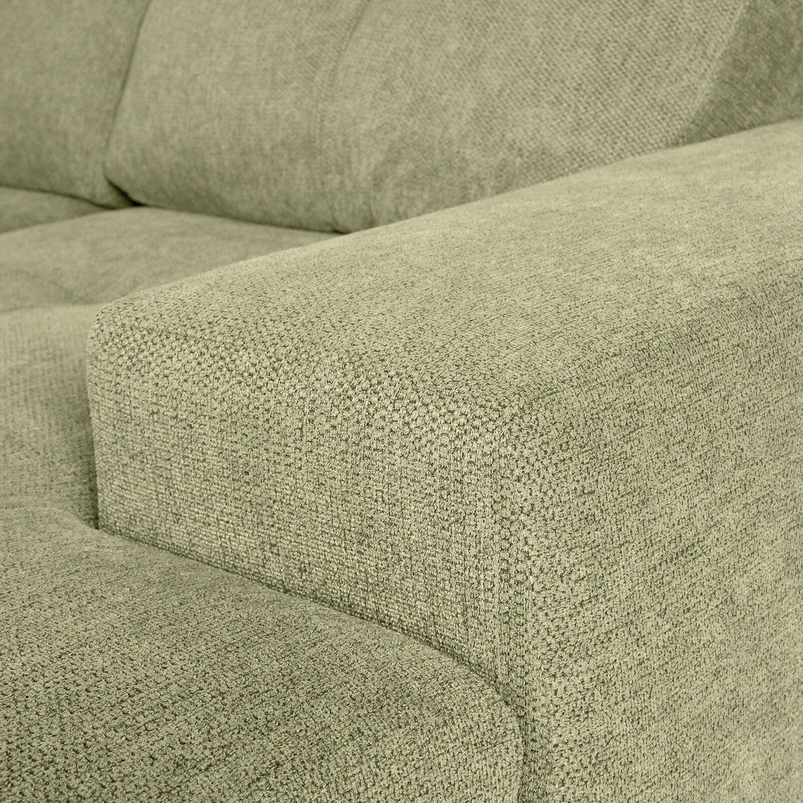 Nahaufnahme einer grünen Sofaecke mit texturierter Stoffoberfläche, Perspektive von der Seite.