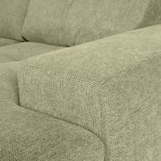 Nahaufnahme einer grünen Sofaecke mit texturierter Stoffoberfläche, Perspektive von der Seite.