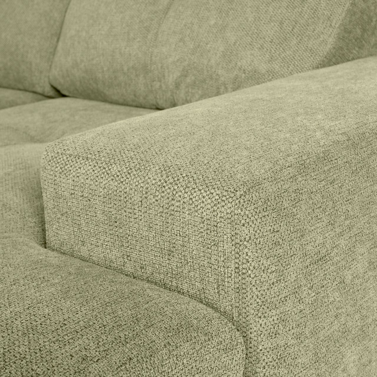 Nahaufnahme einer grünen Sofaecke mit texturierter Stoffoberfläche, Perspektive von der Seite.