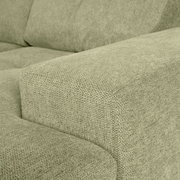 Nahaufnahme einer grünen Sofaecke mit texturierter Stoffoberfläche, Perspektive von der Seite.