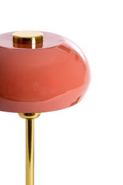 Nahaufnahme einer Tischleuchte mit einem glänzenden, rosafarbenen Lampenschirm und einem goldenen Ständer, seitliche Perspektive.