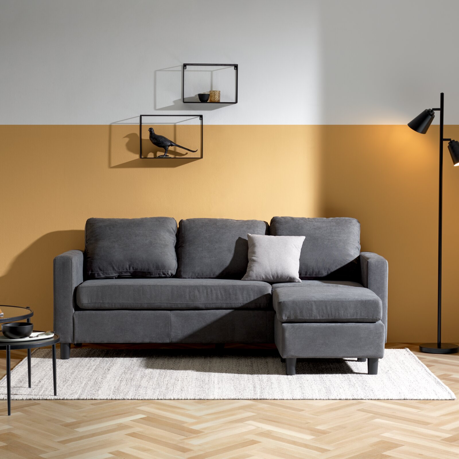 Ti´me Hoekbank TRIXI Grijze bank met poef in een moderne woonkamer, van voren gefotografeerd.