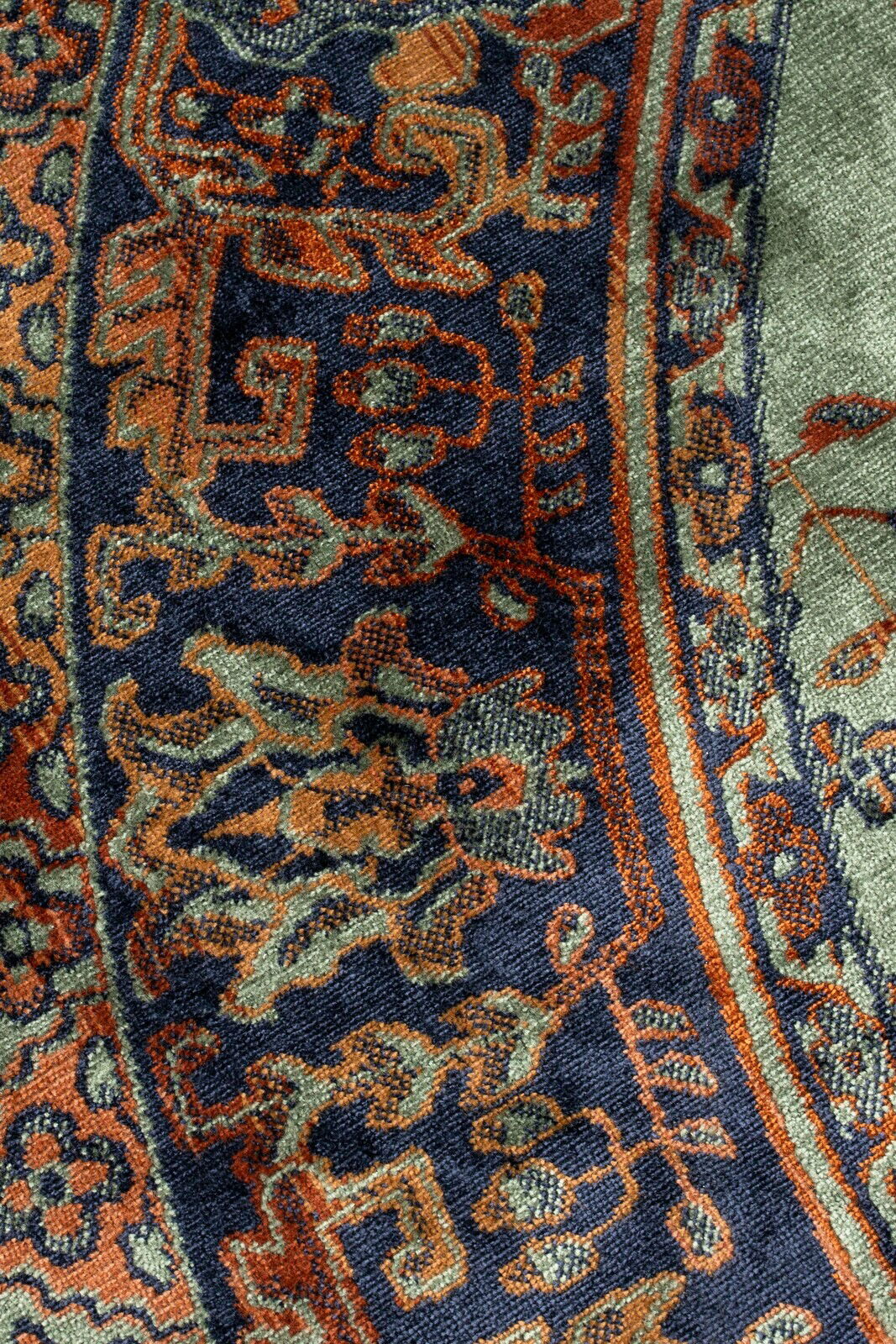 Nahaufnahme eines Teppichs mit orientalischem Muster in Blau, Orange und Grün, von oben betrachtet.