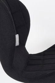 Nahaufnahme eines schwarzen Stuhls mit gepolsterter Rückenlehne und sichtbarem Markenetikett, seitliche Perspektive