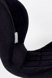 Nahaufnahme eines schwarzen Stuhls mit gepolsterter Rückenlehne und sichtbarem Markenetikett, seitliche Perspektive