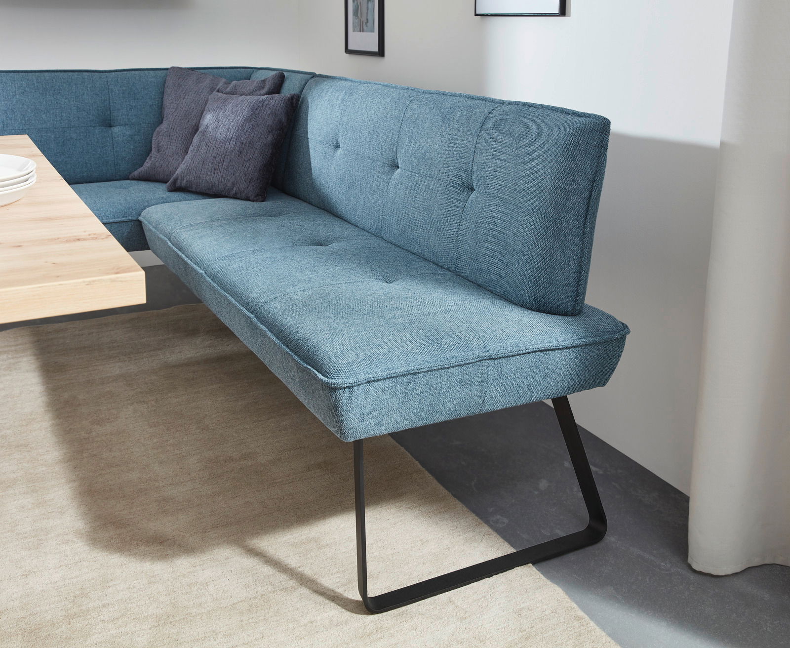 Eckbank in modernem Design mit blauer Polsterung und schwarzen Metallbeinen, seitliche Perspektive