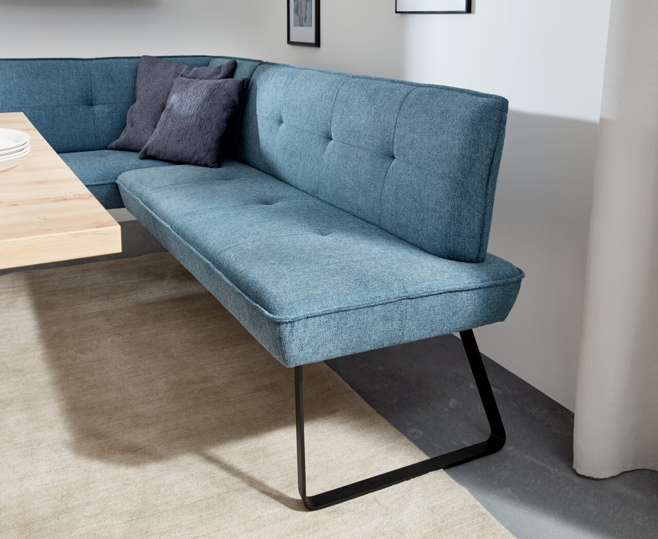 Eckbank in modernem Design mit blauer Polsterung und schwarzen Metallbeinen, seitliche Perspektive