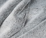 Nahaufnahme einer flauschigen, grauen Wohndecke mit weicher Textur.