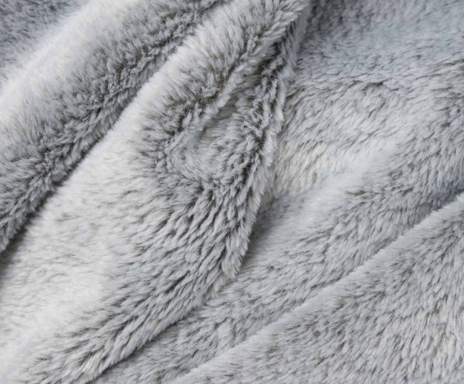 Nahaufnahme einer flauschigen, grauen Wohndecke mit weicher Textur.