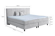 Graues Boxspringbett mit Kopfteil, drei Kissen und blauer Matratzenauflage, seitliche Perspektive