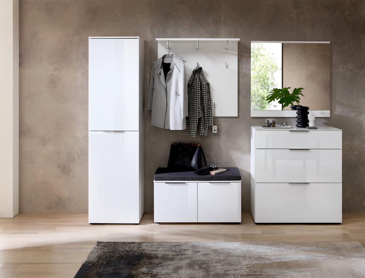 Moderne Garderobeneinrichtung mit weißem Garderobenschrank, Bank mit Stauraum, Garderobenpaneel mit Haken und Spiegel, aus frontaler Perspektive.