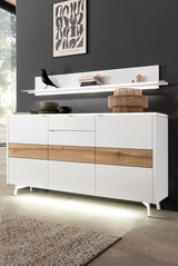 Modernes Sideboard in Weiß mit Holzdetails, frontal fotografiert, mit dekorativer Ablage und Beleuchtung.