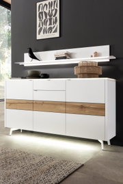 Modern dressoir in wit met houten details, gefotografeerd van voren, met decoratief schap en verlichting.