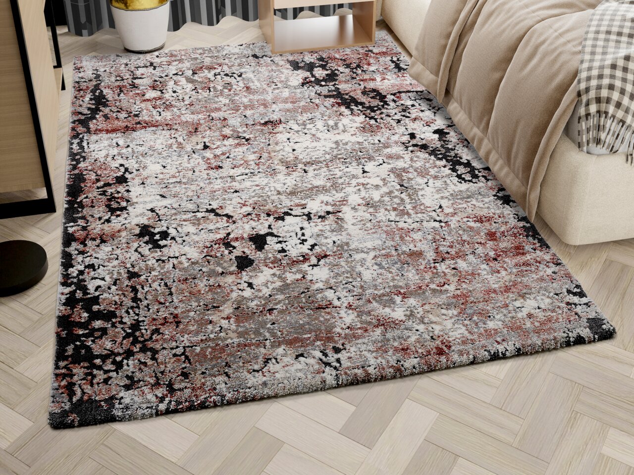 Designer Teppich in einem modernen Schlafzimmer, mit abstraktem Muster in Rot-, Grau- und Schwarztönen, auf hellem Holzboden neben einem Bett. Perspektive von schräg oben.