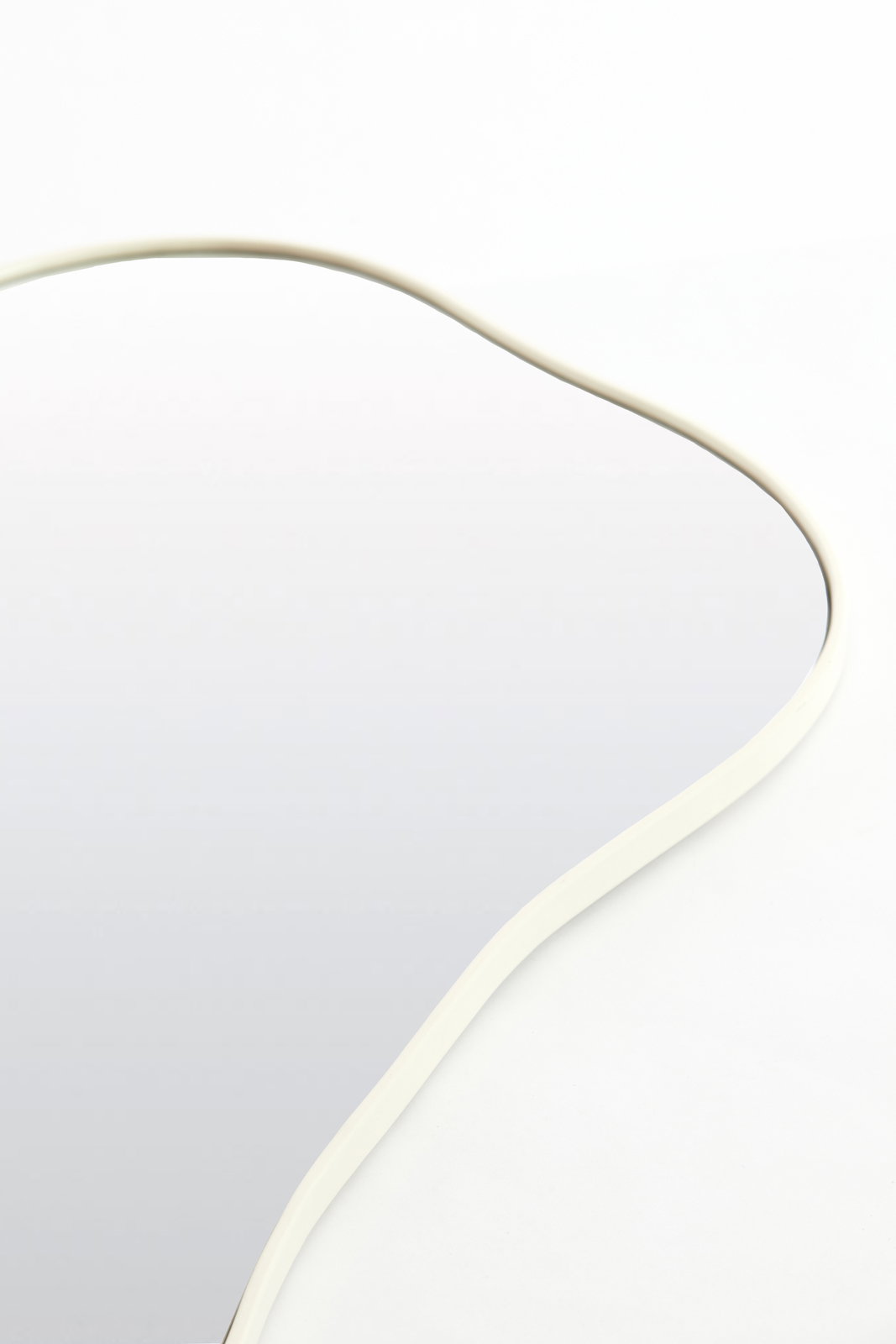 Nahaufnahme eines Spiegels mit geschwungenem, weißem Rahmen aus der Vogelperspektive.