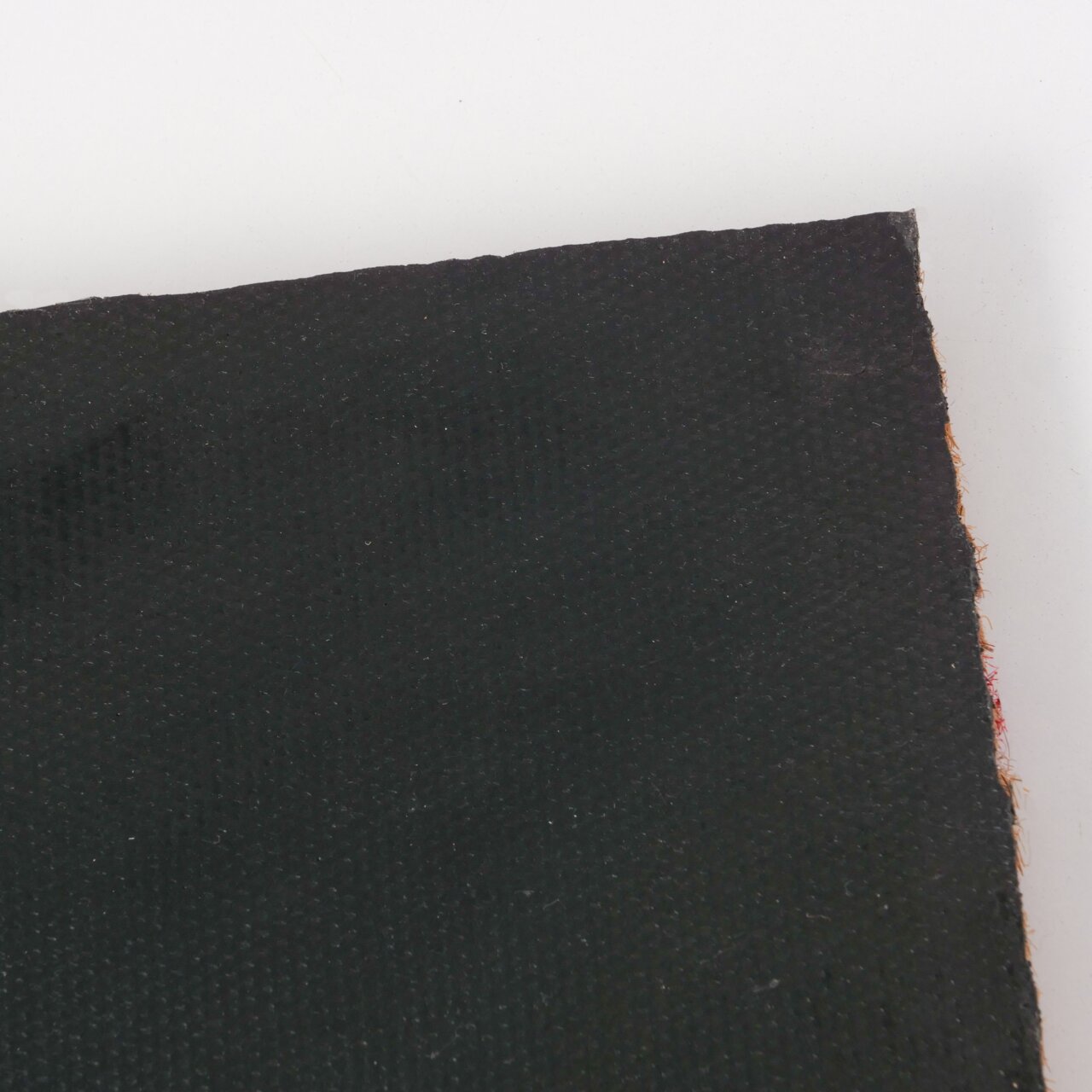 Nahaufnahme der Rückseite einer schwarzen Fußmatte mit strukturierter Oberfläche, von oben fotografiert.