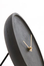 Nahaufnahme einer modernen, minimalistischen Uhr mit schwarzem Zifferblatt und goldenen Zeigern, seitliche Perspektive.