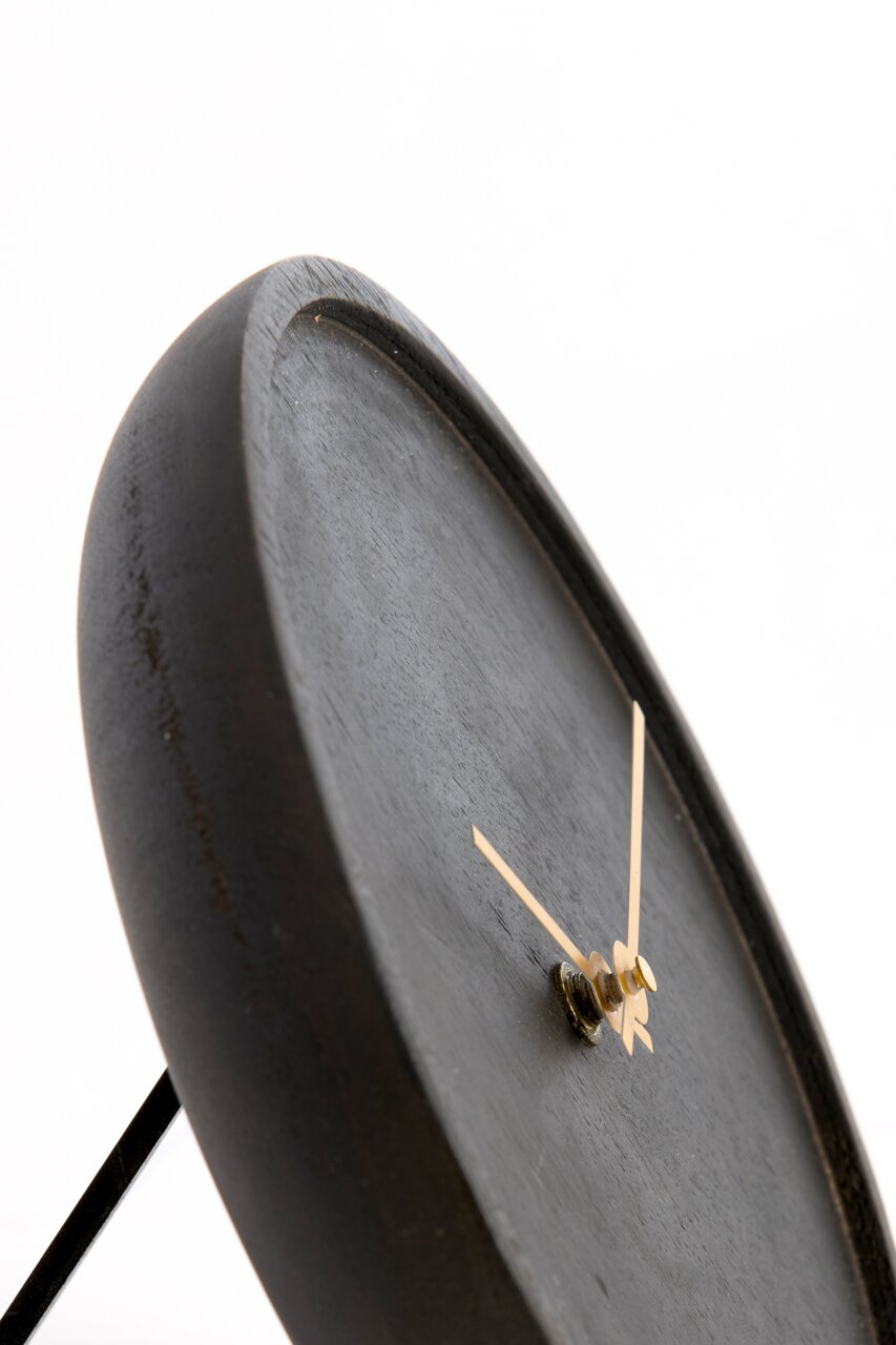 Nahaufnahme einer modernen, minimalistischen Uhr mit schwarzem Zifferblatt und goldenen Zeigern, seitliche Perspektive.
