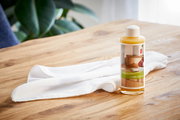 Flasche Renuwell Möbelöl auf einem Holztisch mit weißem Tuch, seitliche Perspektive
