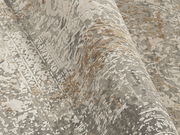 Nahaufnahme eines Designer-Teppichs mit abstraktem Muster in Grau- und Beigetönen, perspektivisch von der Seite aufgenommen.