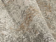 Nahaufnahme eines Designer-Teppichs mit abstraktem Muster in Grau- und Beigetönen, perspektivisch von der Seite aufgenommen.