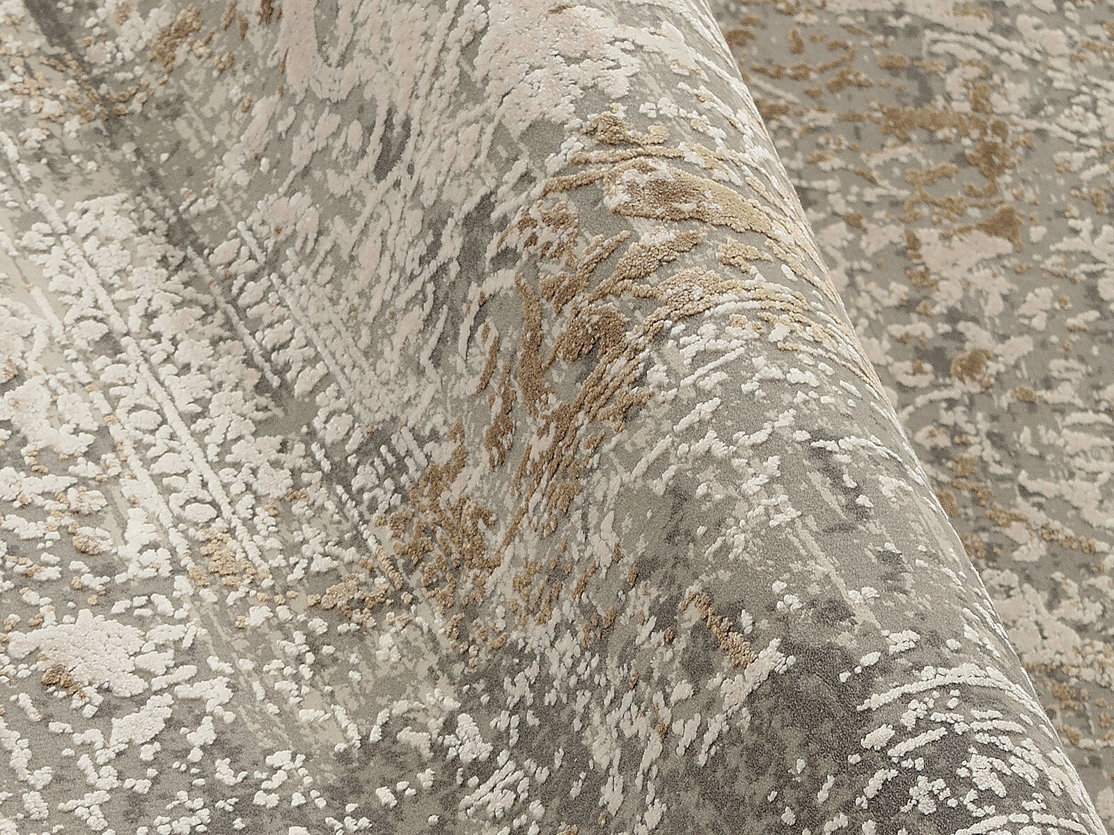 Nahaufnahme eines Designer-Teppichs mit abstraktem Muster in Grau- und Beigetönen, perspektivisch von der Seite aufgenommen.