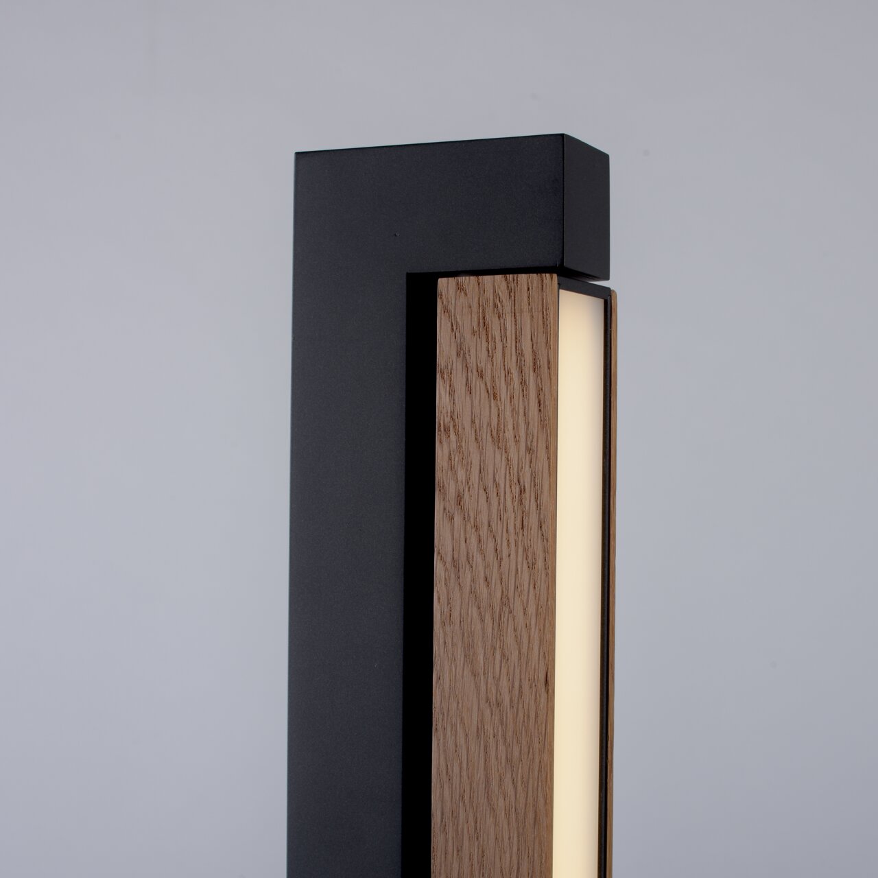 Close-up van de staande lamp PURE-LINES met een modern ontwerp, een zwart metalen frame en een houten bekleding.