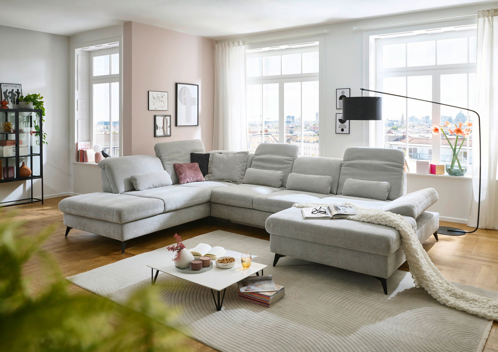 Moderne Polsterrundecke in hellem Grau in einem stilvoll eingerichteten Wohnzimmer, seitliche Perspektive.