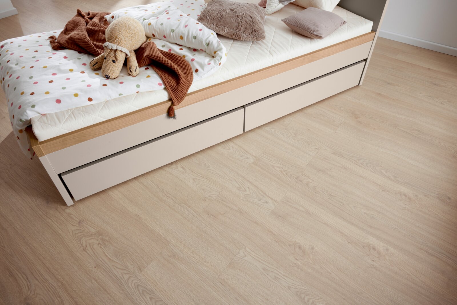 Bettkasten mit zwei Schubladen unter einem Bett, von oben fotografiert, mit Bettwäsche und Kuscheltier.