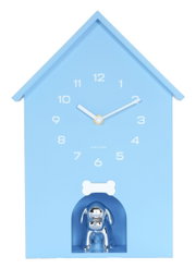 Blaue Wanduhr in Form eines Hauses mit weißen Ziffern und Zeigern, darunter eine silberne Hundefigur in einer kleinen Nische. Frontalansicht.