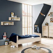 Kinderzimmer mit einem Einzelbett in hellem Holz, von der Seite betrachtet, umgeben von modernen Möbeln und Dekorationen.