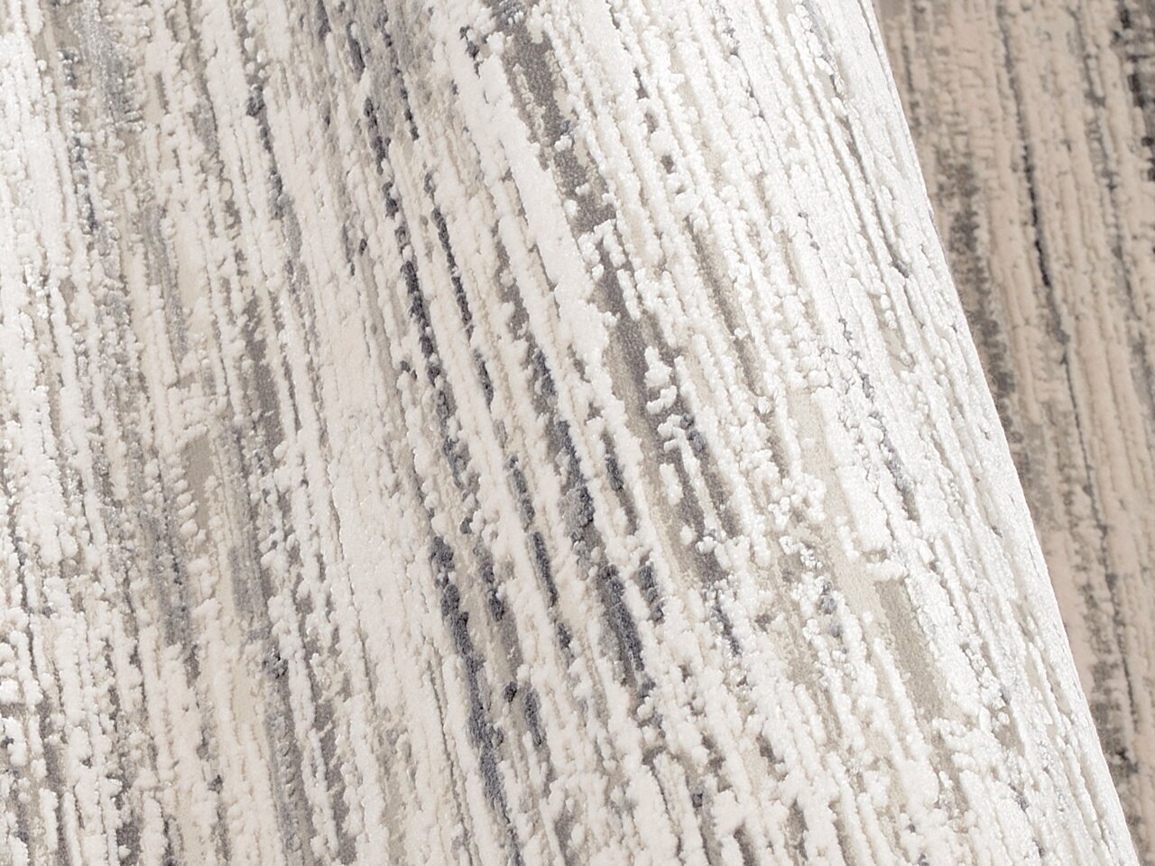 Nahaufnahme eines Designer Teppichs mit abstraktem Muster in Grautönen, seitliche Perspektive
