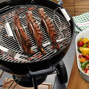 Spare Rib Halter auf einem Grill mit gegrillten Rippchen, seitliche Perspektive