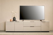 Modernes weißes TV-Lowboard mit Flachbildfernseher, Vase mit Blüten und kleiner Deko-Vase auf minimalistischer Wohnzimmereinrichtung, Frontalansicht.