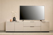 Modernes weißes TV-Lowboard mit Flachbildfernseher, Vase mit Blüten und kleiner Deko-Vase auf minimalistischer Wohnzimmereinrichtung, Frontalansicht.