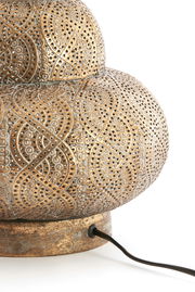 Nahaufnahme eines kunstvoll verzierten Lampenfußes aus Metall mit filigranen Mustern und einem Kabel, seitliche Perspektive.