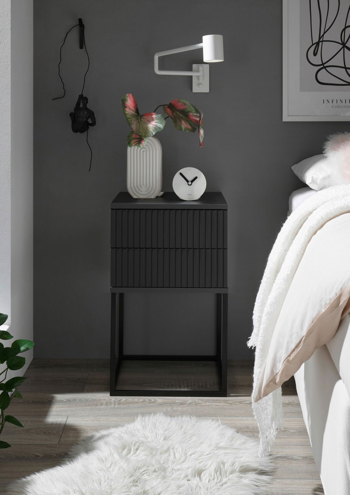 Moderne schwarze Nachtkommode mit geriffelter Oberfläche, dekoriert mit einer Vase und einer Uhr, seitliche Perspektive.