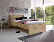 Modernes Holzbett in einem hellen Raum mit großen Fenstern, seitliche Perspektive