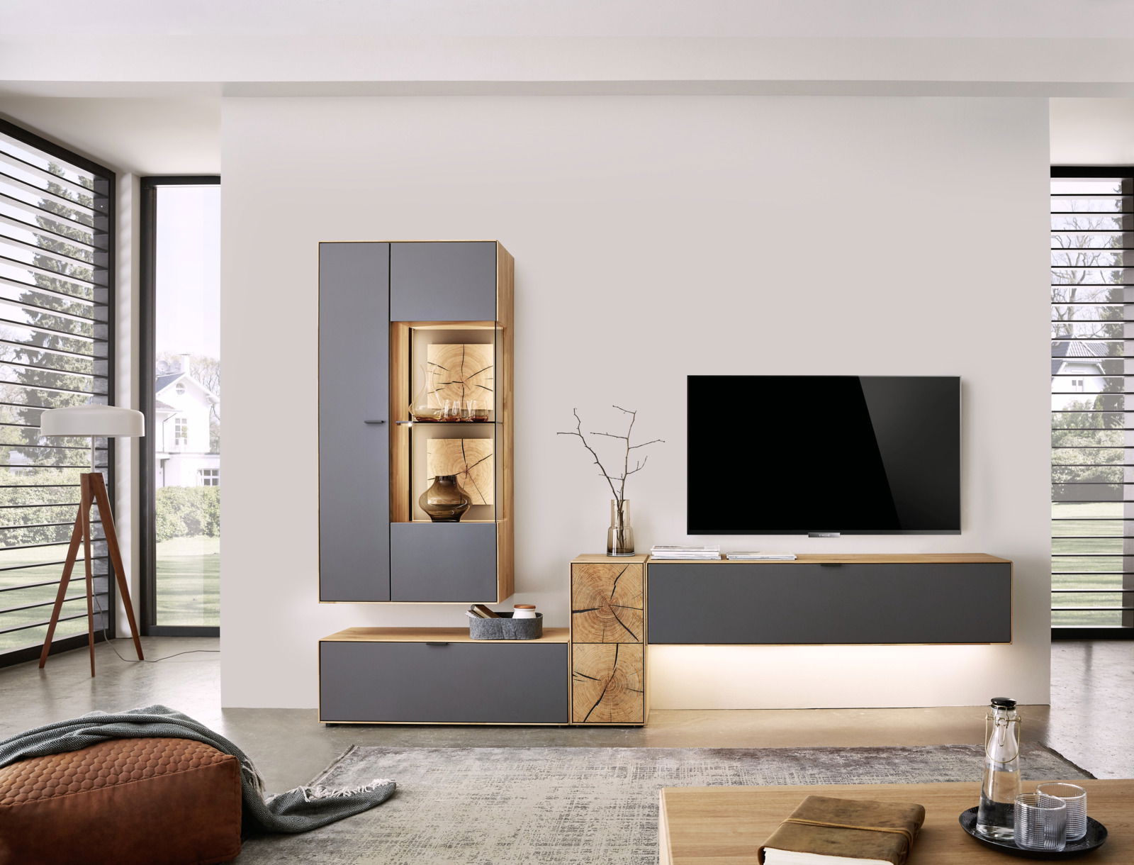 Wöstmann Markenmöbel Wandkombination WM 2410 Moderne Wandkombination in einem Wohnzimmer mit grauen und holzfarbenen Elementen, bestehend aus einem Hängeschrank mit Vitrine und einem TV-Board, seitliche Perspektive.