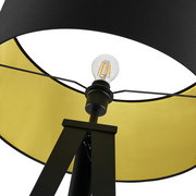 Nahaufnahme einer Stehleuchte von unten, mit schwarzem Schirm und gelber Innenseite, sichtbare Glühbirne.