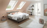 Modernes Polsterbett in einem stilvollen Schlafzimmer mit Dachfenstern, seitliche Perspektive.