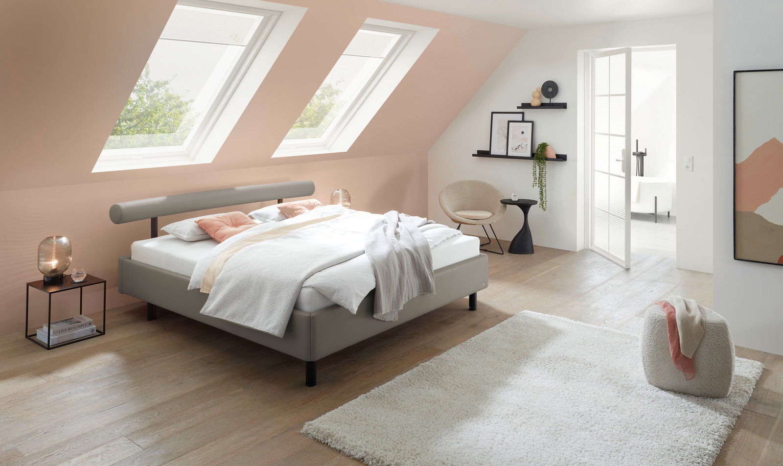 Modernes Polsterbett in einem stilvollen Schlafzimmer mit Dachfenstern, seitliche Perspektive.
