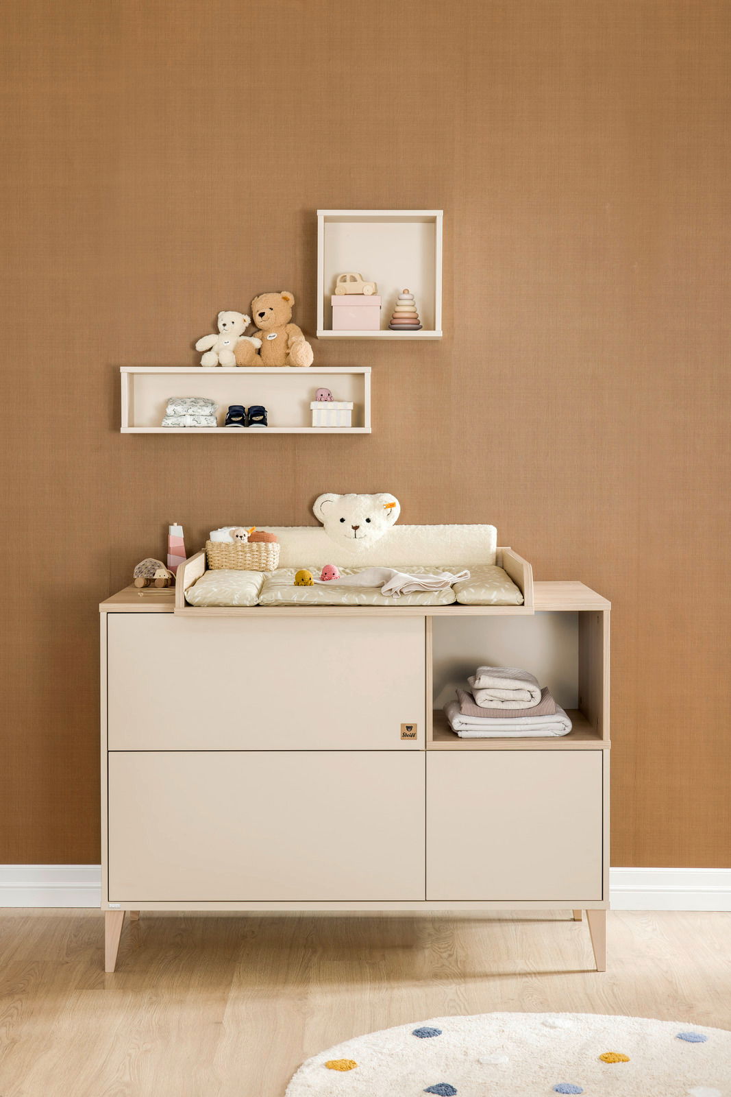 Vorderansicht einer Wandbox quadratisch, dekoriert mit Spielzeug und Accessoires, an einer braunen Wand über einer Kommode.