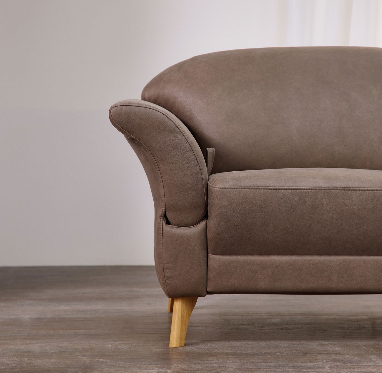 Nahaufnahme eines braunen Sofas mit Holzbeinen, seitliche Perspektive