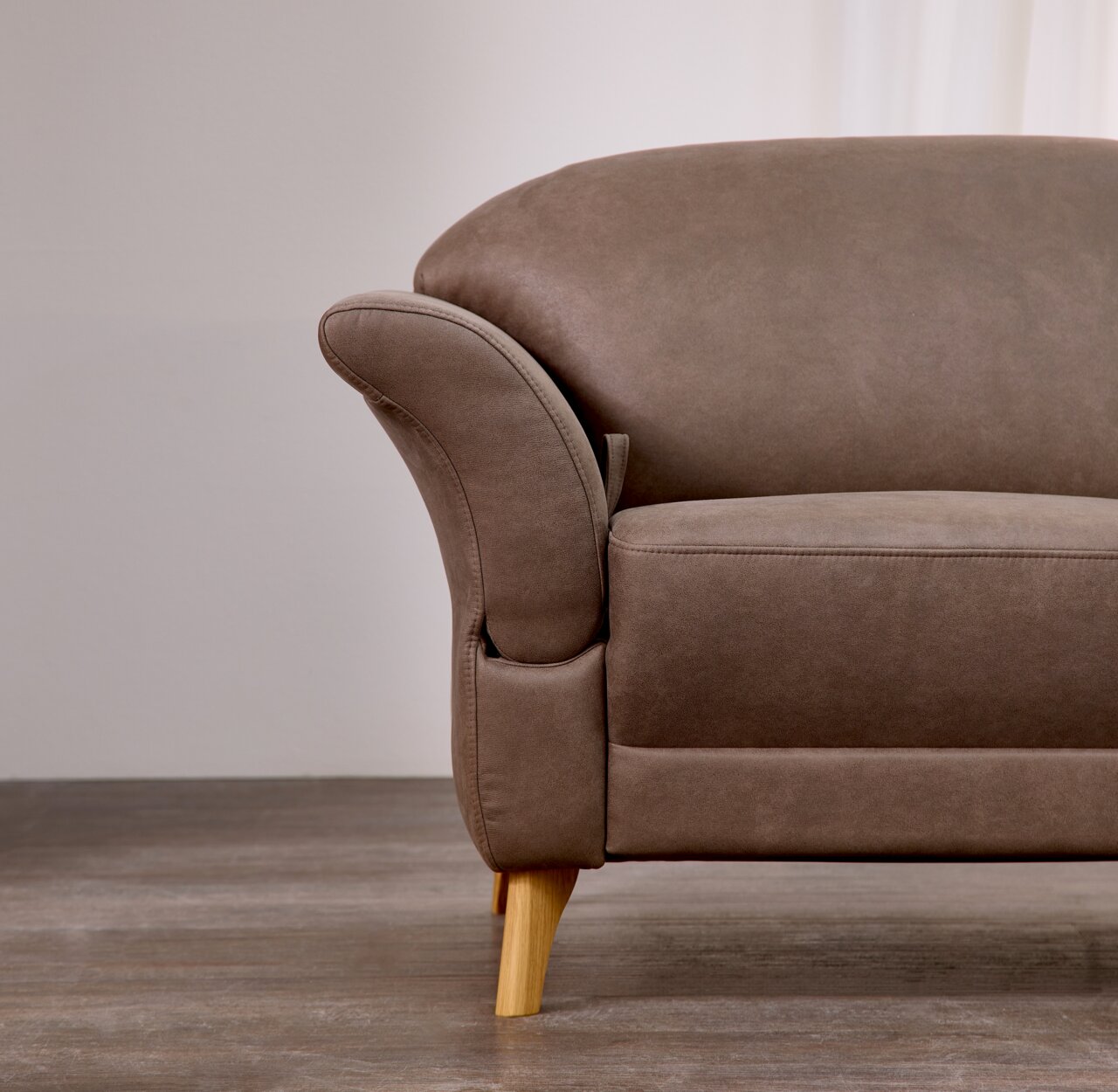 Nahaufnahme eines braunen Sofas mit Holzbeinen, seitliche Perspektive