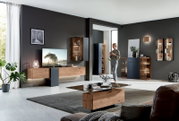 Moderne Wohnzimmer-Wandkombination in Holzoptik mit integrierter Beleuchtung, aus der Perspektive eines offenen, hellen Raumes betrachtet.