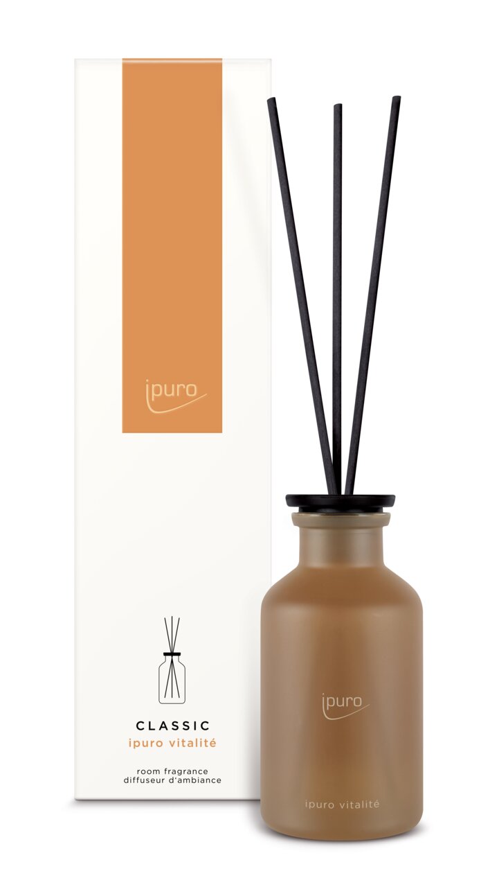 Raumduft Classic Vitalité von ipuro in einer braunen Flasche mit schwarzen Duftstäbchen, frontal abgebildet vor der Verpackung.