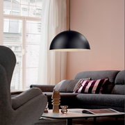 Schwarze, halbkugelförmige Pendelleuchte mit matter Oberfläche über grauem Sofa im Wohnzimmer, Seitenansicht leicht von unten